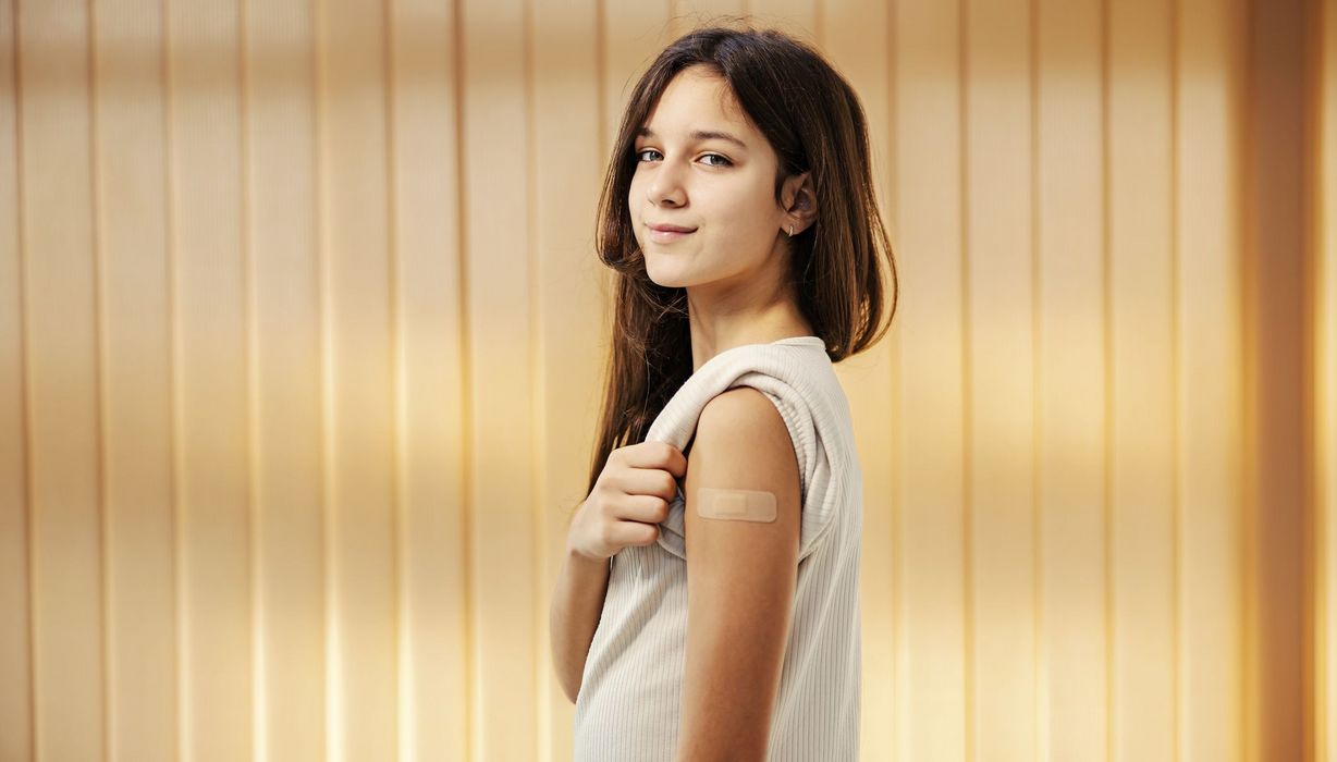 Junges Mädchen zeigt Impfstelle am Arm 