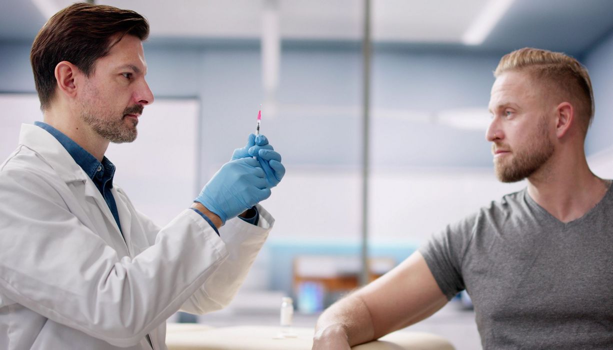 Ein Arzt bereitet eine Spritze für einen Patienten vor.