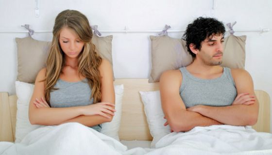 Mann und Frau, sitzen nebeneinander aufrecht im Bett und sind sichtlich frustriert.