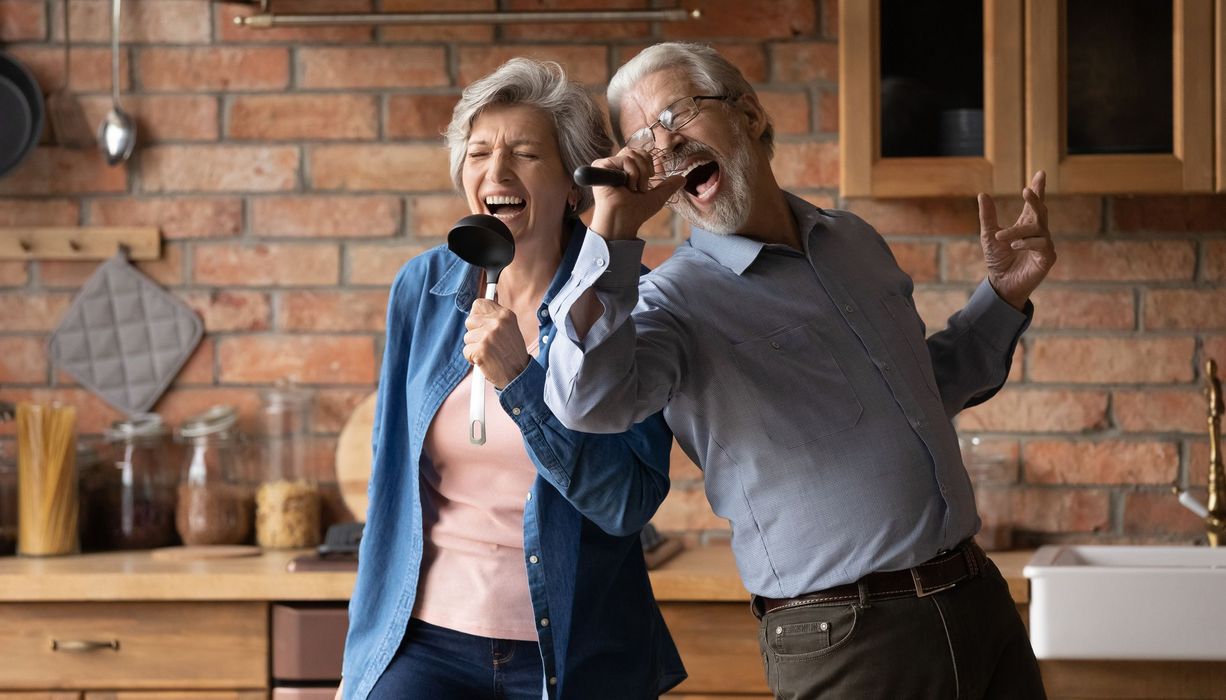 Zwei ältere Senioren, singen zusammen in der Küche.