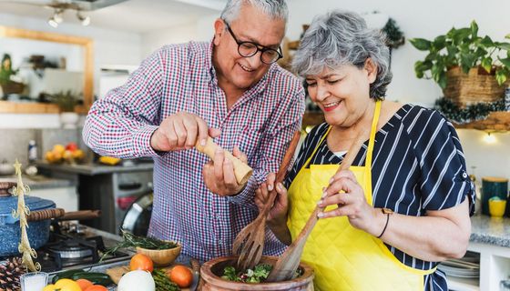 Älteres Paar kocht zusammen, sie wirken glücklich.