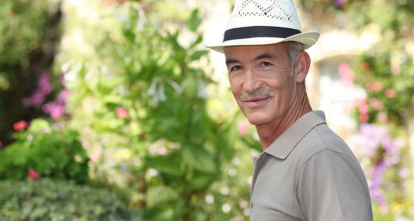 Mann mit Strohhut und Polo-Shirt draußen im Schatten