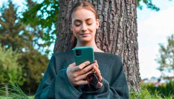 Junge Frau, schaut in ihr Smartphone.