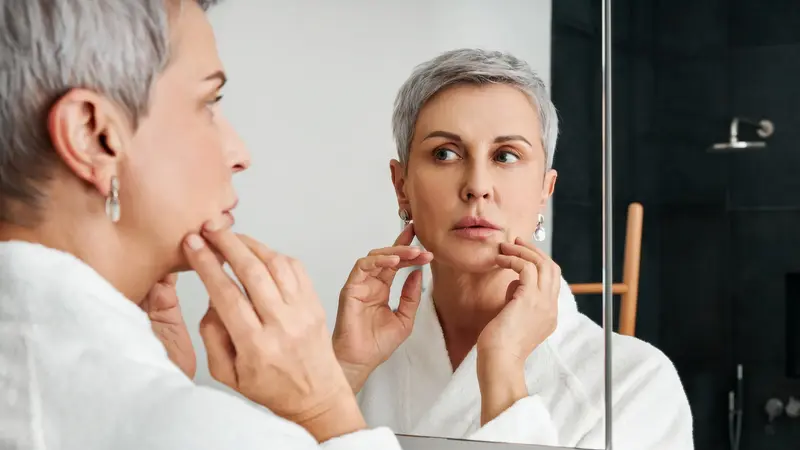 Lippenherpes: Frau betrachtet ihr Gesicht im Spiegel.