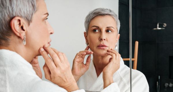 Lippenherpes: Frau betrachtet ihr Gesicht im Spiegel.