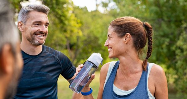 Sportliche Frau 40+ trinkt aus einer Flasche.