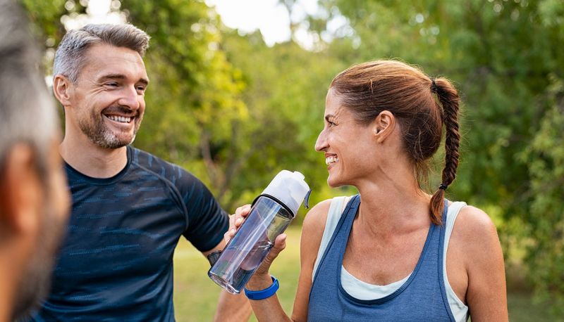 Sportliche Frau 40+ trinkt aus einer Flasche.