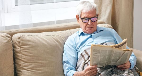 Senior sitzt auf der Couch und liest.