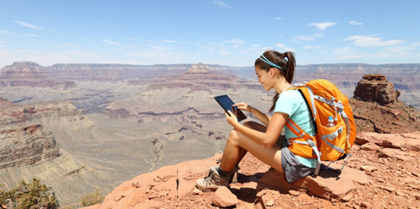 Junge Frau mit Rucksack und Tablet-Computer in der Wildnis.