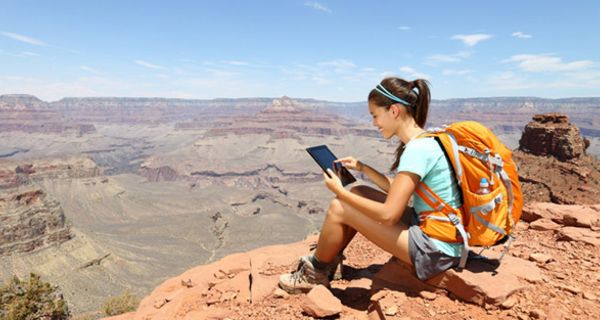 Junge Frau mit Rucksack und Tablet-Computer in der Wildnis.