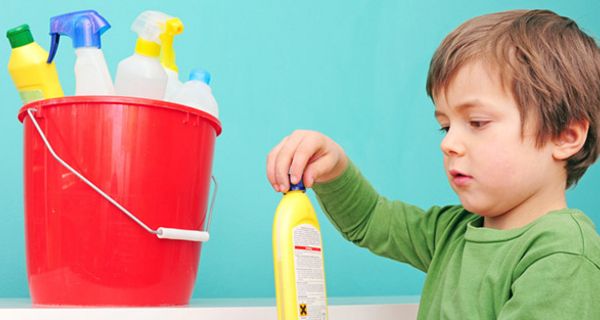 Junge, ca. 3 Jahre, roter Putzeimer mit Putzmitteln, gelbe Flasche in der Hand, versucht sie aufzumachen