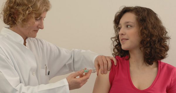 Junge Frau wird von Ärztin in den Oberarm geimpft