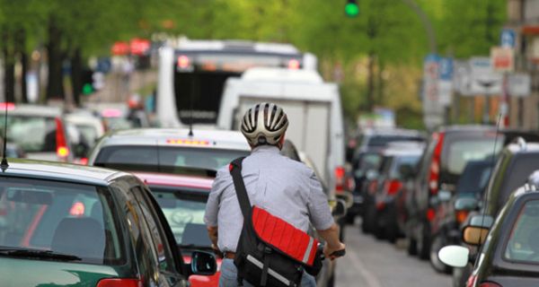 Fahrradfahrer im Berufsverkehr mit Auto-Stau