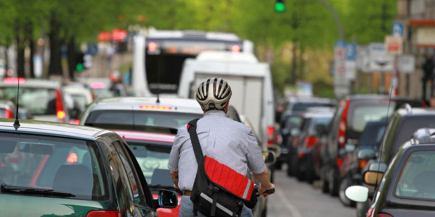 Fahrradfahrer im Berufsverkehr mit Auto-Stau