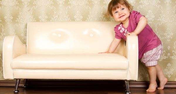 Kleines Mädchen, barfuß, stützt sich auf eine Kindercouch