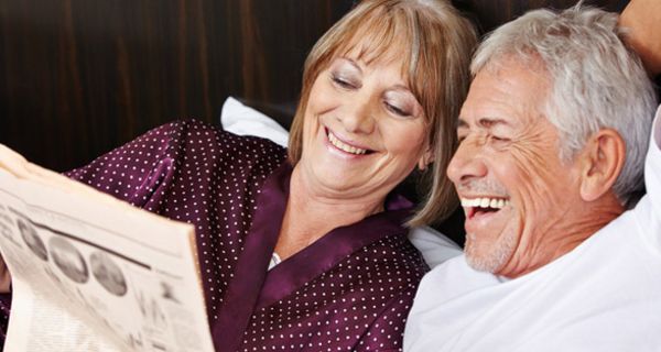 Gut gelauntes, vitales, älteres Paar liest lachend eine Zeitung