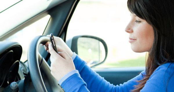 Frau bedient während der Fahrt ihr Handy.