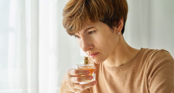 Frau, riecht an einem Fläschchen Parfum.