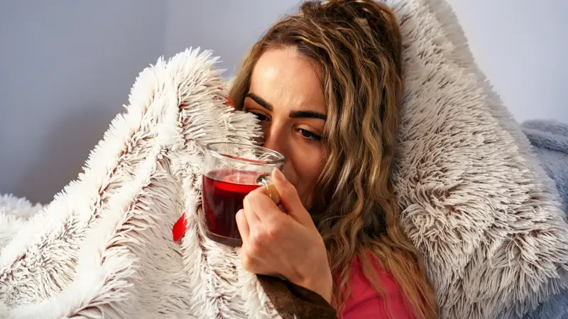 Frau mit Tee, dick zugedeckt.