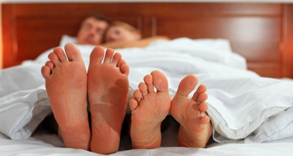 Frau und Mann im Bett schauen auf ihre nackten Füße