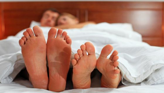 Frau und Mann im Bett schauen auf ihre nackten Füße