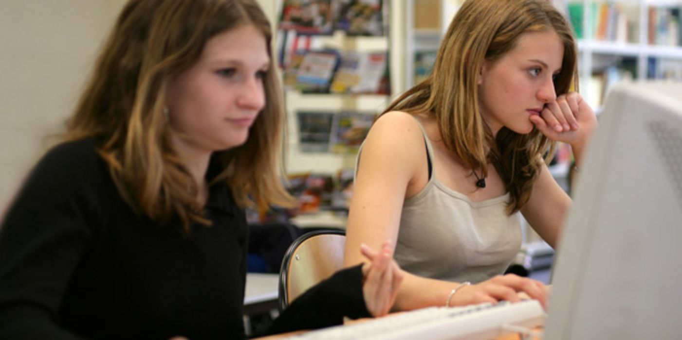 Zwei Teenagerinnen an Schul-Computern