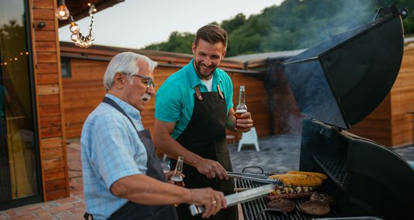 Älterer Mann, grillt zusammen mit seinem Sohn.