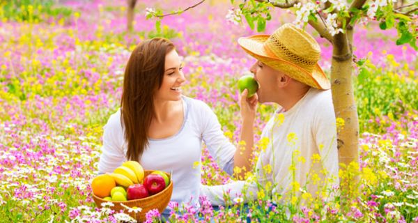 Junges Paar isst Obst auf Blumenwiese.