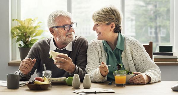 Älteres Paar isst zusammen am Tisch.