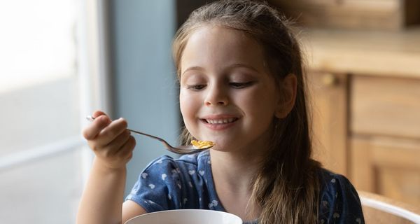 Kind, etwa fünf Jahre alt, isst Cornflakes.