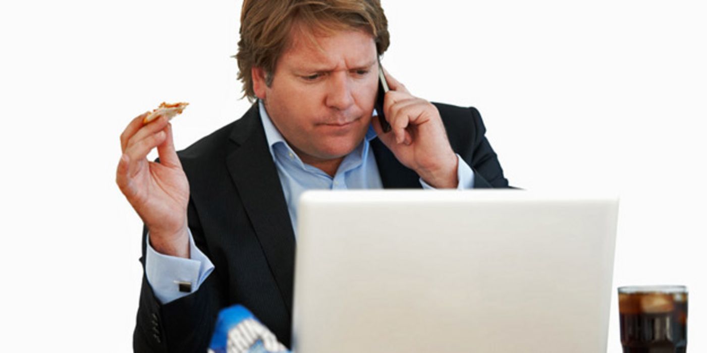 Essender Mann mit Telefon am Ohr und Blick auf den PC