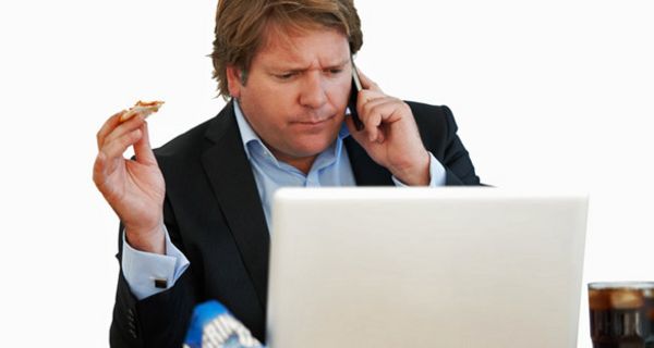 Essender Mann mit Telefon am Ohr und Blick auf den PC