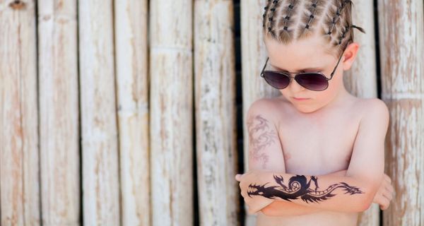 Kleiner Junge mit Sonnenbrille und Klebe-Tatto auf dem Arm.