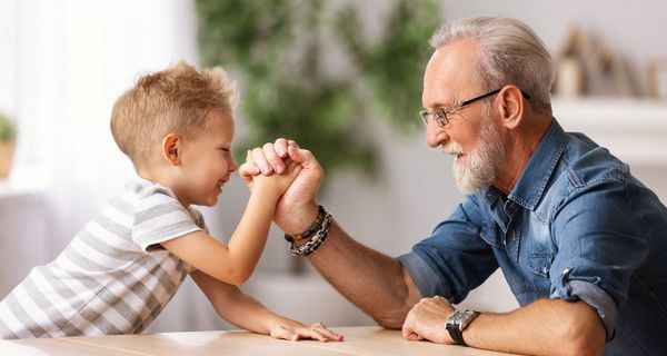 Älterer Mann macht Armdrücken mit seinem Enkel.