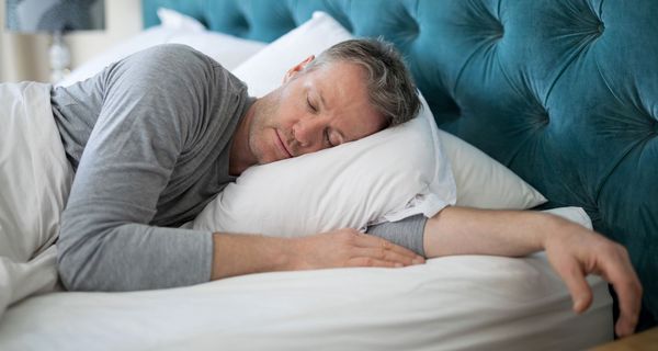 Mann schläft im Bett.