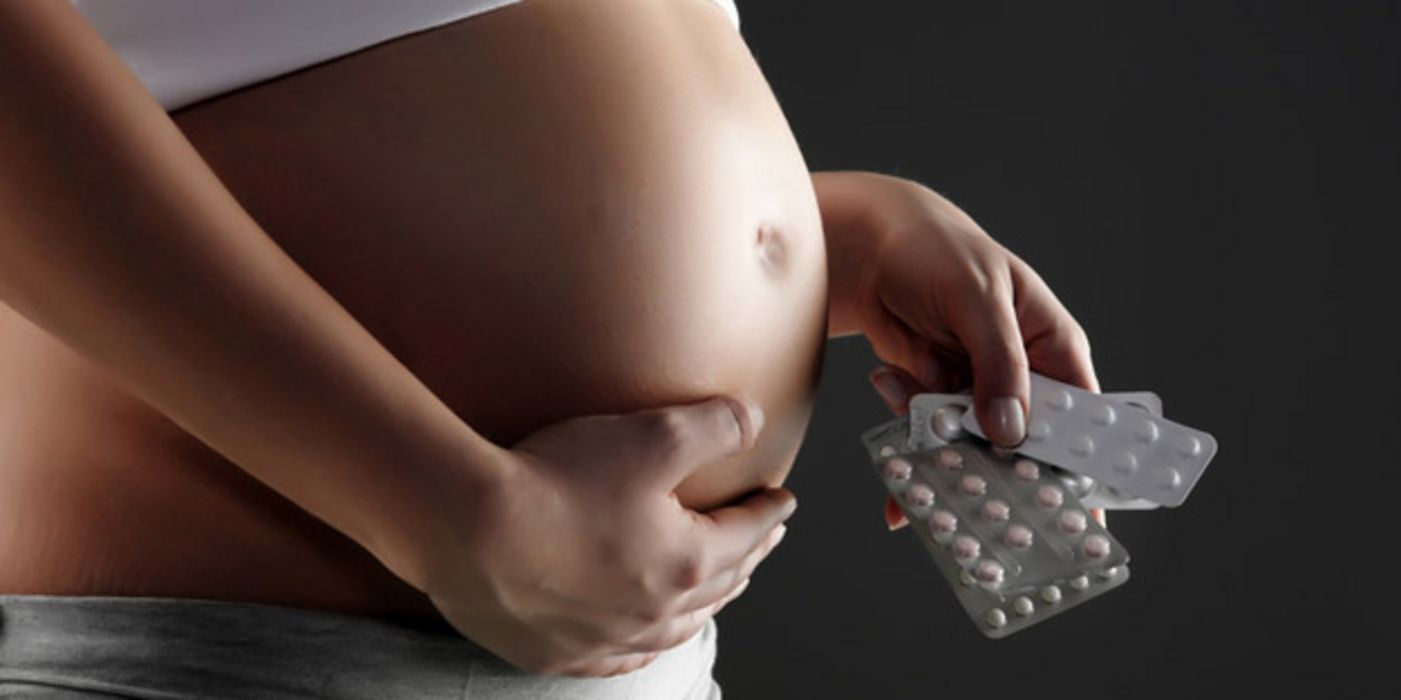 Schwangere hält Medikamente in der Hand