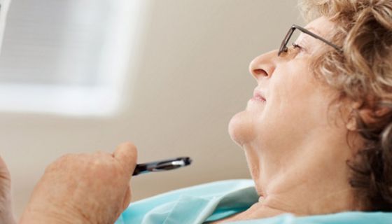 Profilansicht bis Bluse: Seniorin mit Brille und grauen Lockenkopf beim Kreuzworträtseln