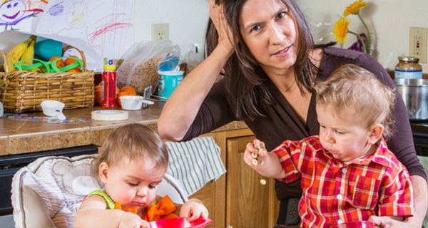 Entnervt schauende Mutter in Küche mit 2 Kleinkindern