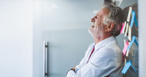 Gestresster älterer Mann, lehnt an der Wand.