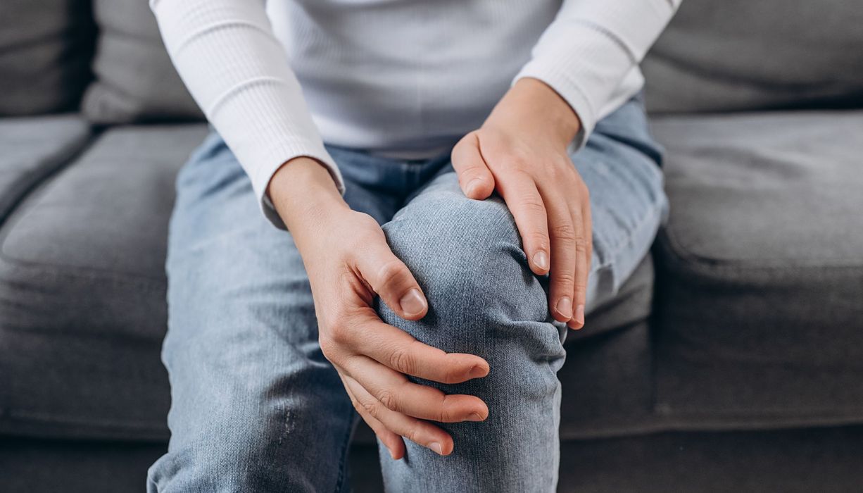 Frau, hält ihre Hände an ihre Knie.