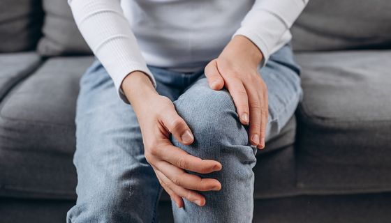 Frau, hält ihre Hände an ihre Knie.