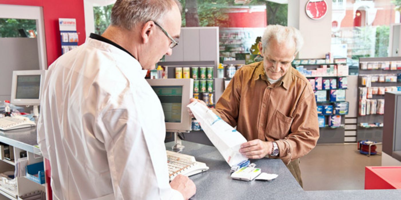 Beratungszene in Apotheke: Apotheker überprüft Hausapotheke eines Kunden