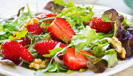 Bunte Blattsalate mit Erdbeeren und Walnüssen auf weißem Teller