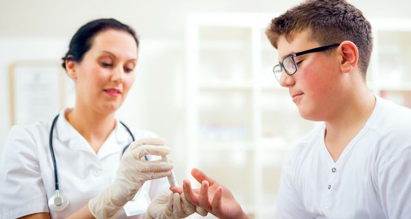 Ärztin misst bei einem Jungen den Blutzucker.