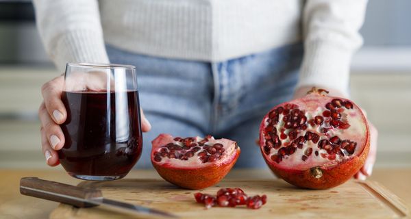 Frau vor einem Glas Saft und Granatapfel. 