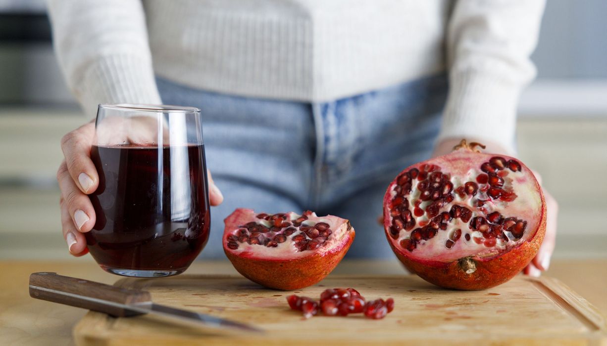 Frau vor einem Glas Saft und Granatapfel. 