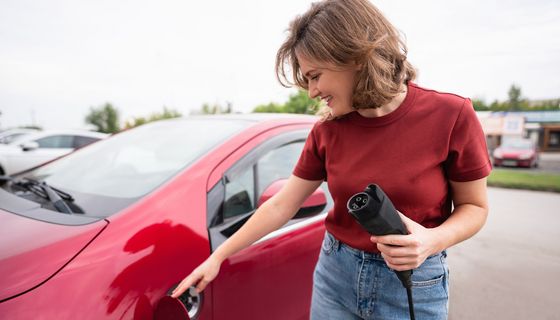 Eine Frau lädt ihr Elektro-Fahrzeug.