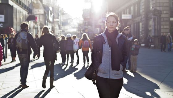 Junge Frau, läuft auf einer Straße mit vielen Menschen.