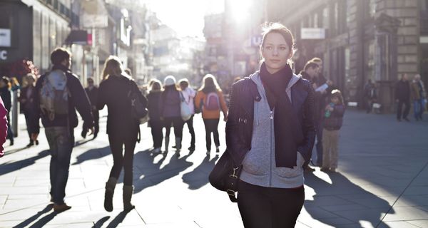 Junge Frau, läuft auf einer Straße mit vielen Menschen.