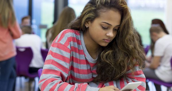 Jugendliche, sitzt in der Schule mit ihrem Smartphone.